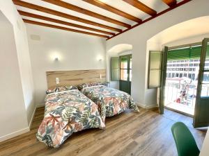 a bedroom with two beds and a large window at La Despensa de la Corredera Hostal in Córdoba