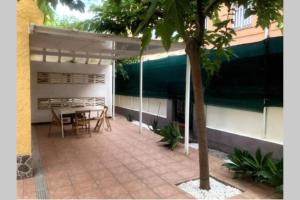 een patio met een tafel en stoelen en een boom bij Villa exclusiva cerca del mar con Piscina privada in Benicàssim
