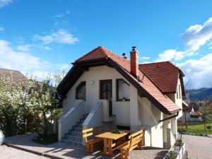 une petite maison blanche avec une table en bois et un banc dans l'établissement Apartment Knap, à Cerknica