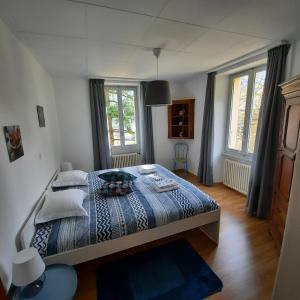 a bedroom with a bed with a blue comforter and two windows at La Pergola by Quokka 360 - for mountain sports enthusiasts in Lavorgo