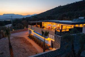 a large house with a sunset in the background at Corleone - Modern Villa with Jacuzzi in Kalkan in Kas