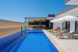 una piscina con sillas y sombrillas junto a una casa en Corleone - Modern Villa with Jacuzzi in Kalkan en Kas