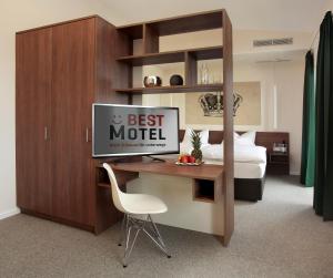 a hotel room with a desk with a bed and a tv at Best Motel in Vilsbiburg