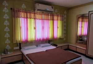 a room with a bed and a window with colorful curtains at Hotel Ayodhya in Chiplun