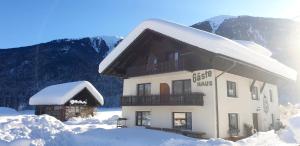 un edificio cubierto de nieve con montañas de fondo en Guesthouse Schoba Typ D, en Kirchbach