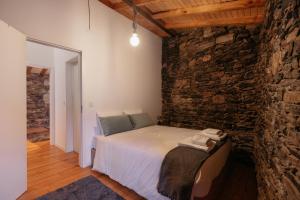 a bedroom with a bed and a stone wall at Casa Gaveto in Sabugal