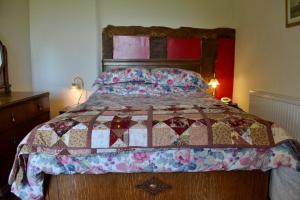 a bedroom with a bed with a quilt on it at Broome Park Farm B&B in Cleobury Mortimer