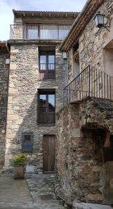 Casa de piedra con puerta de madera y balcón en cal dalmau apartaments loft, en Pardines