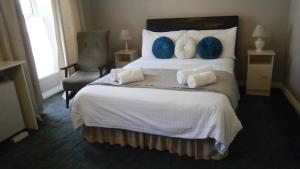 a bedroom with a large bed with blue pillows and a chair at Ilenroy House in Skibbereen