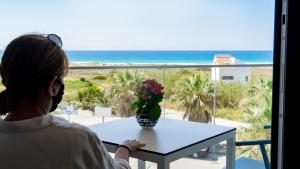 Una donna seduta a un tavolo che guarda l'oceano di Hotel Playa de la Plata a Zahara de los Atunes