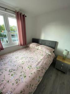 a bedroom with a bed with a pink comforter and a window at 92 Lake View in Caernarfon