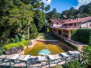 a house with lounge chairs and a pool of water at Pousada das Montanhas in Monte Verde