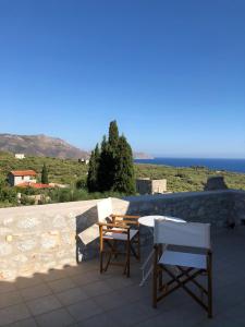 a patio with two chairs and a table and a view of the ocean at Kamares Stone House 5 in Gerolimenas