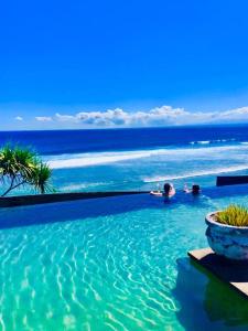 a swimming pool with the ocean in the background at The Palms Ceningan Hotel in Nusa Lembongan
