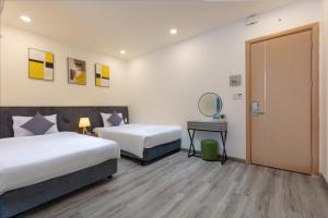 ニャチャンにあるNha Trang Moony Hotelのベッド2台と鏡が備わるホテルルームです。