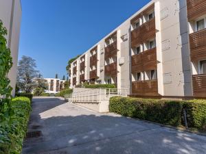 an apartment building with bushes next to a sidewalk at Vacancéole - Résidence L'Ile d'Or in La Londe-les-Maures