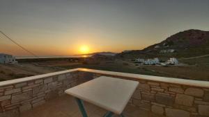a bench on a balcony with the sunset in the background at Armonia Studios, Apartments & Villa in Mikri Vigla