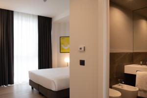 a bedroom with a bed and a bathroom with a sink at Hotel Punta Tipa in Trapani
