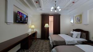 a hotel room with two beds and a television at Hotel Maroqanda in Samarkand