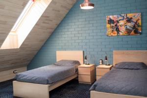 two beds in a bedroom with a blue wall at Franciscan guest house in Klaipėda