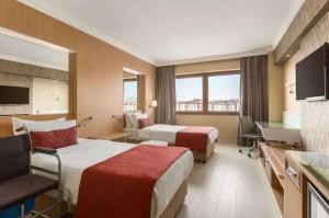 a hotel room with two beds and a desk at Ramada Usak in Usak