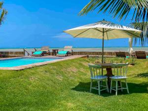 - une table avec un parasol et des chaises à côté de la piscine dans l'établissement Pousada Villa Tatuamunha, à Porto de Pedras