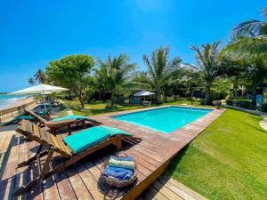 - une piscine avec une terrasse et des chaises à côté de l'océan dans l'établissement Pousada Villa Tatuamunha, à Porto de Pedras