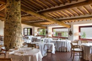 una sala da pranzo con tavoli e sedie bianchi di Hotel Le Fontanelle a Castelnuovo Berardenga