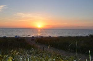 a sunset on the beach with the sun setting at Appartementanlage Villa Granitz 45 in Göhren