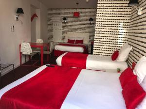 - une chambre avec 2 lits dotés de draps rouges et blancs dans l'établissement Hôtel Concorde, à Mâcon