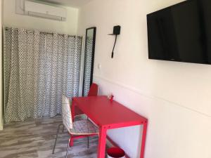 une table rouge avec des chaises et une télévision murale dans l'établissement Hôtel Concorde, à Mâcon