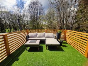 a patio with a couch and tables on the grass at Apartman Loggia Park & Free Parking in Žilina