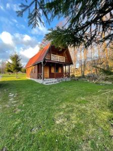 a log cabin with a red roof on a grass field at Sikaszoi vizimalom in Sicasău