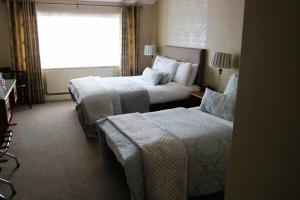 a hotel room with two beds and a window at New Park Hotel Athenry in Athenry