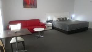 a hotel room with a bed and a red couch at Gunnedah Lodge Motel in Gunnedah