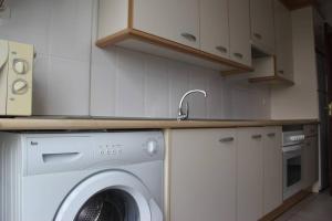 a kitchen with a washing machine and a sink at Apartamento en Miño con vistas a la Ría. in Miño