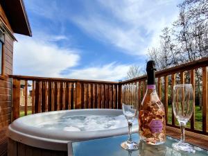 a bottle of wine and two glasses on a hot tub at The Deneb in Amotherby