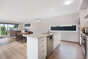 a kitchen with white cabinets and a dining room with a table at Milawa Vineyard Views - Guesthouse 2 in Milawa