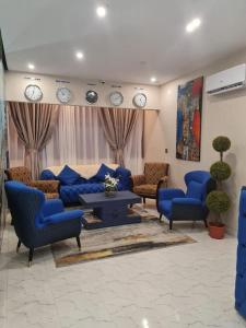 a living room with blue furniture and clocks on the wall at Residence DB in Luanda