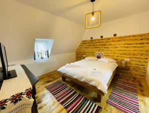 1 dormitorio con 1 cama y pared de madera en Conacul maramureșean Bilgăr en Bogdan Vodă