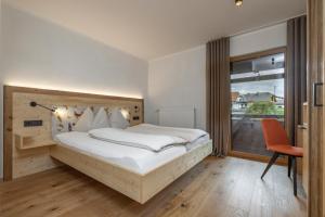 a bedroom with a bed and a desk and a window at Hotel Winkler-Tuschnig in Weissensee