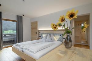 a bedroom with a bed with a vase with flowers at Hotel Winkler-Tuschnig in Weissensee