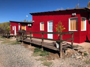 a red building with benches in front of it at Cabañas Buen Aike in Malargüe