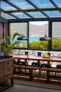 a dining room with a table and a view of the ocean at Hout & About Guest House in Hout Bay