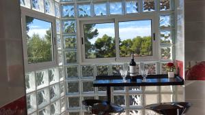 Habitación con pared de cristal, mesa y 2 ventanas. en Villa Porta Caeli, en Tarragona