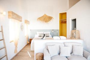a white bedroom with a bed and a couch at Le Chalet du Papa in Gruissan