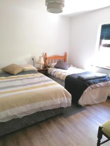 Harbourside House Glengarriff في غليغاريف: سريرين في غرفة نوم مع أرضيات خشبية
