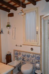 a blue and white bathroom with a toilet and a window at La Dimora di Gaspare in Locogrande