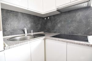 a kitchen with a sink and white cabinets at Moderne Ferienwohnung mit Sat-TV & WLAN in Leverkusen