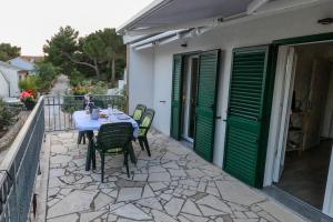 una mesa y sillas en un patio con puertas verdes en KN House with two apartments near sea en Rogoznica